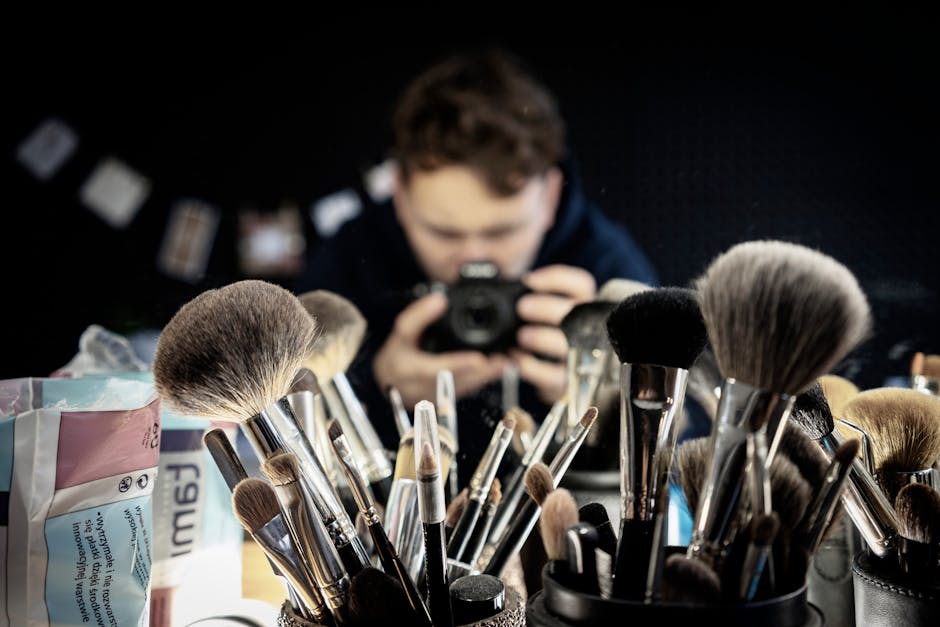 Creative focus on makeup brushes with a blurred photographer's reflection in the background.